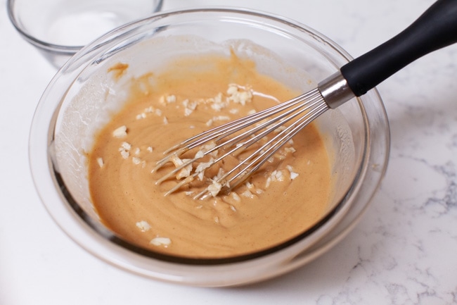 almost done making peanut sauce in a glass Pyrex bowl with a small whisk