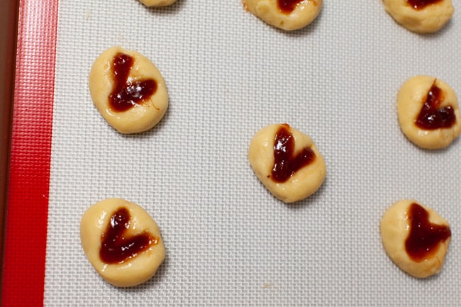 heart shaped thumbprint cookies on a silicon baking mat