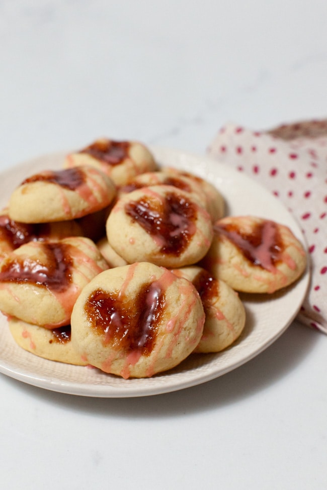 heart shaped thumbprint cookies on a plate with a napkin in the background
