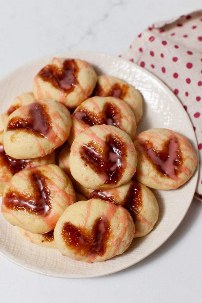 heart shaped thumbprint cookies on a plate with a napkin in the background