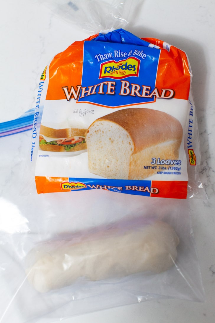 bag of Rhodes Frozen White Bread and a frozen dough loaf in a plastic zip top bag on a kitchen counter