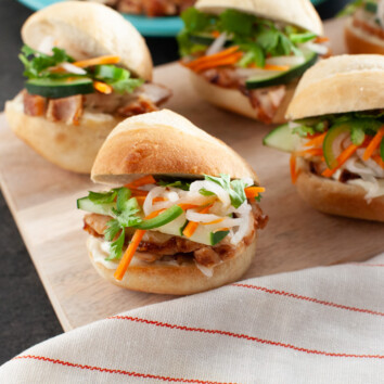 chicken banh mi sliders on a wooden board with a striped napkin in the foreground